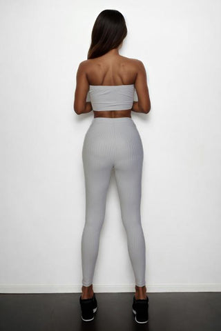 Back view of model wearing ribbed tube top and leggings set in gray, polyester and spandex blend, featuring a bodycon fit.
