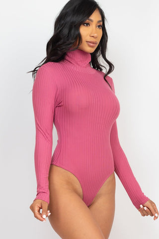Model wearing pink ribbed turtle neck long sleeve bodysuit, highlighting soft, high stretch fabric, ideal for stylish comfort.