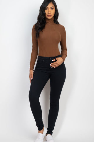 Woman wearing a ribbed turtleneck long sleeve bodysuit in brown, paired with black jeans, showcasing style and comfort.