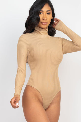 Model wearing a ribbed turtle neck long sleeve bodysuit in beige, showcasing fitted design and high stretch rib knit fabric.