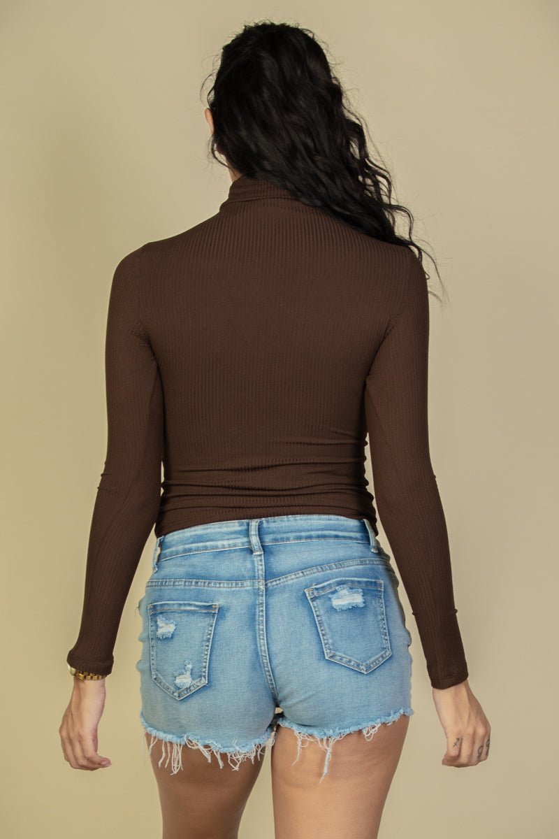 Model wearing a brown ribbed turtleneck long sleeve top paired with denim shorts, showcasing back view, highlighting fabric texture.