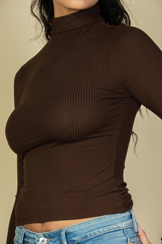 Model wearing brown ribbed turtleneck long sleeve top, showcasing soft and lightweight high stretch fabric, paired with blue jeans.