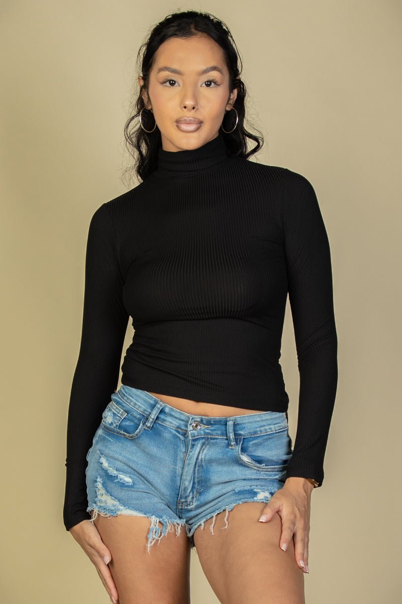 Model wearing black ribbed turtleneck long sleeve top paired with distressed denim shorts against a neutral background.