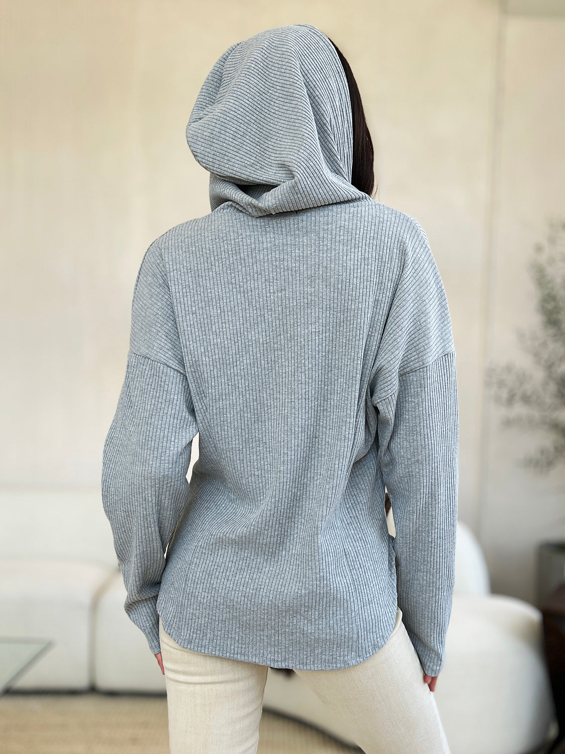 Woman wearing full-size ribbed zip-up drawstring hooded jacket in gray, back view, showcasing casual style and comfortable fit.