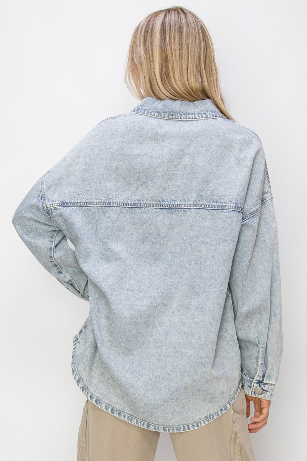 Woman wearing Risen Button Up Long Sleeve Shacket in light denim, showcasing back view with long sleeves and relaxed fit.