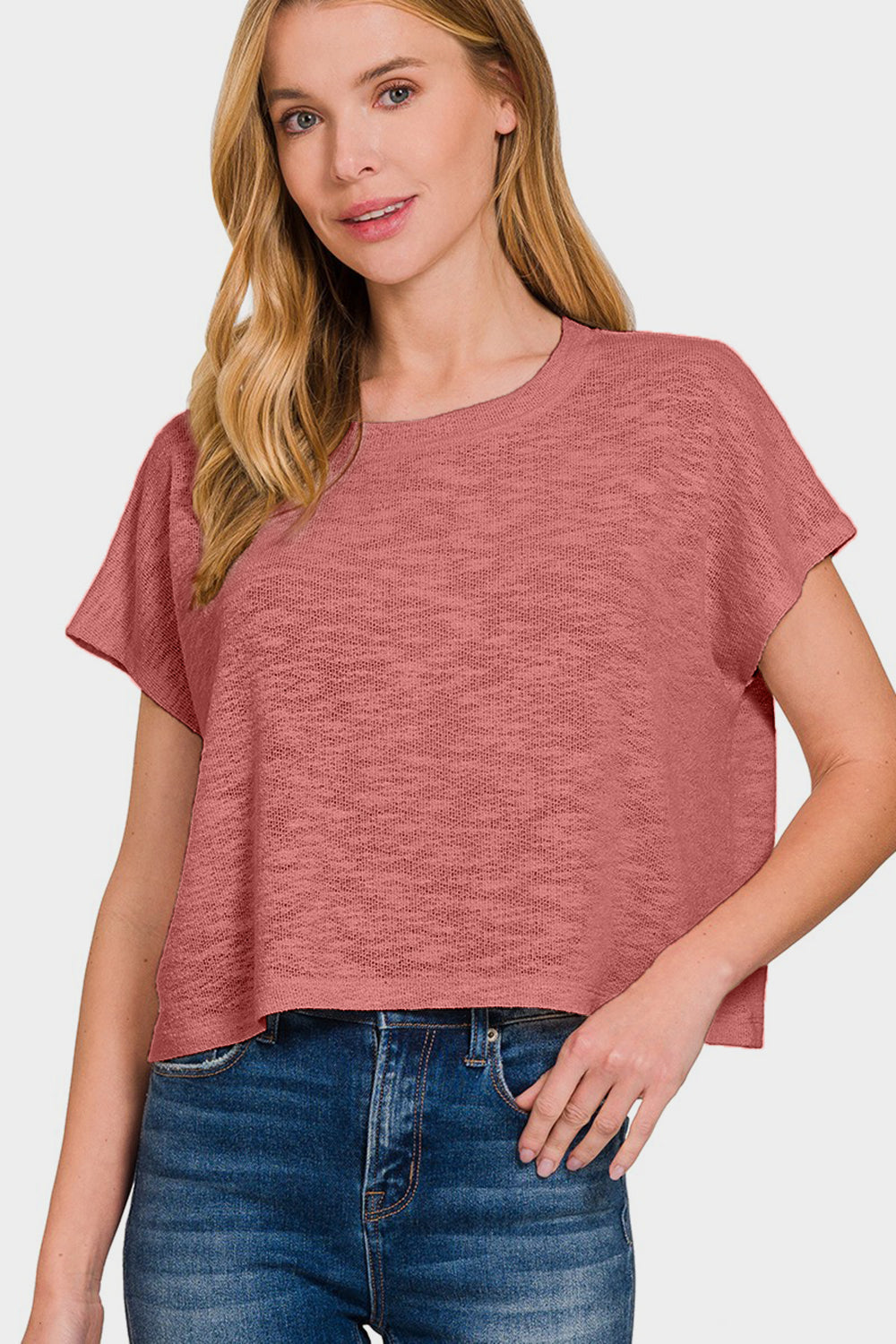 Woman wearing a casual round neck short sleeve t-shirt in rose color, slightly stretchy fabric, paired with blue jeans.