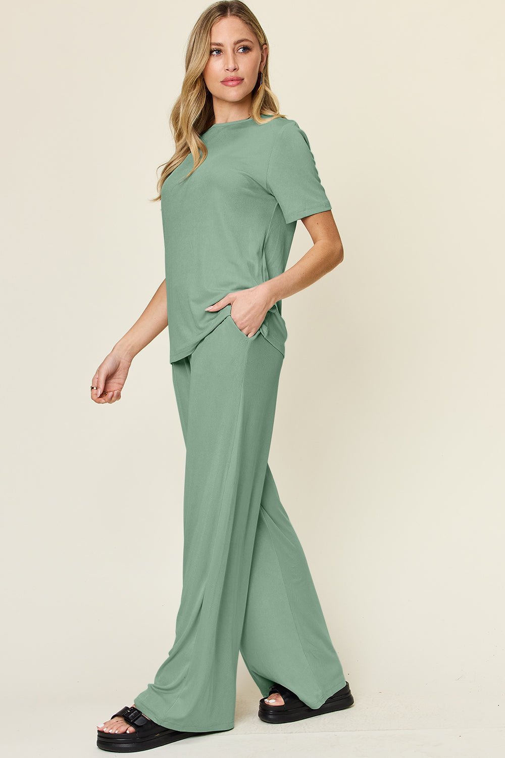 Woman wearing a green round neck short sleeve t-shirt and wide leg pants set, showcasing a basic style two-piece outfit.