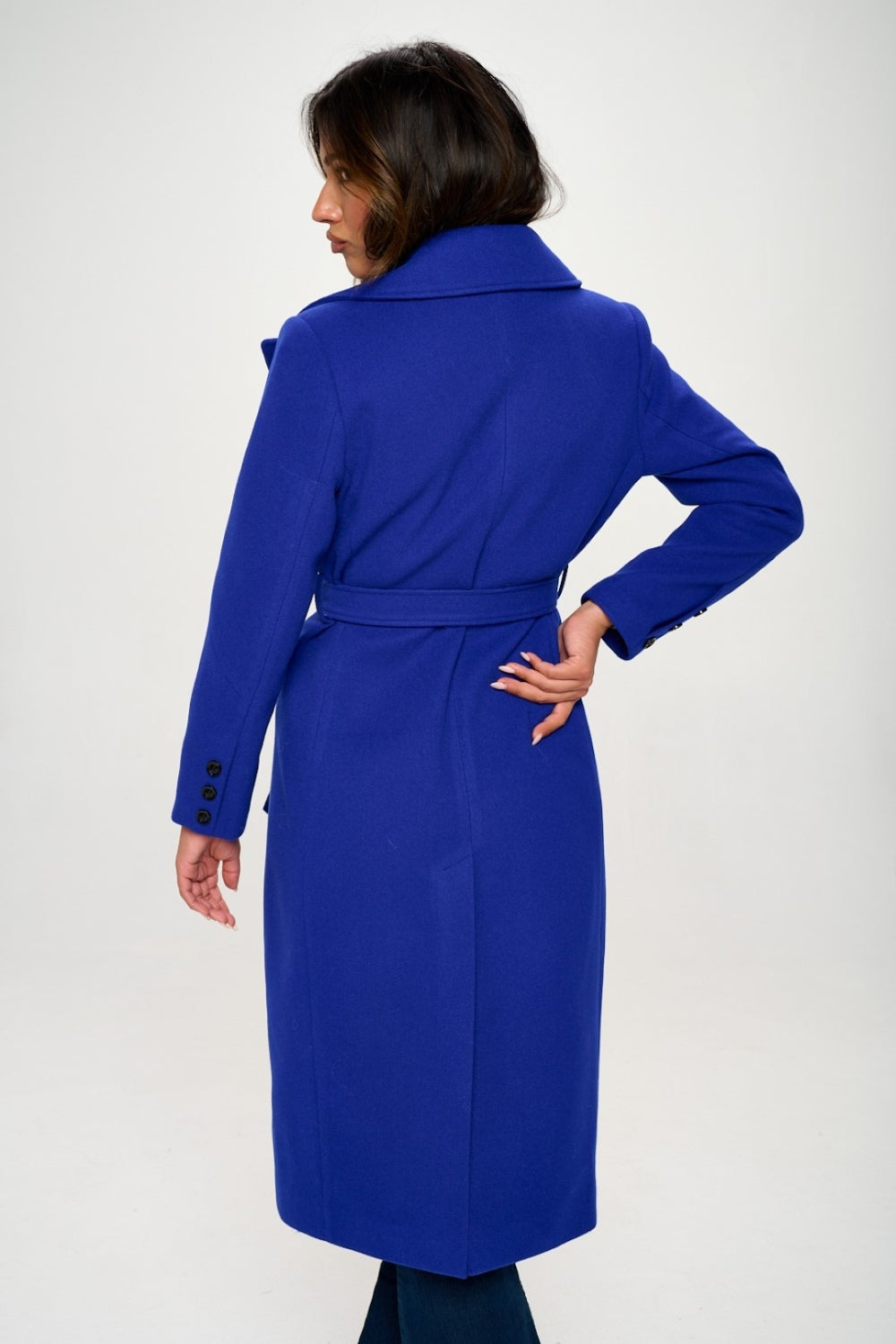 Woman in royal blue double-breasted longline belted coat showcasing a sophisticated silhouette from the back.