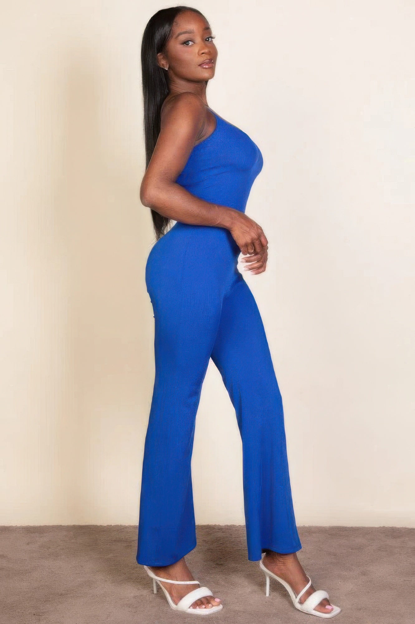 Woman wearing a royal blue ribbed sleeveless wide-leg jumpsuit with spaghetti straps, showcasing an elegant and chic silhouette.