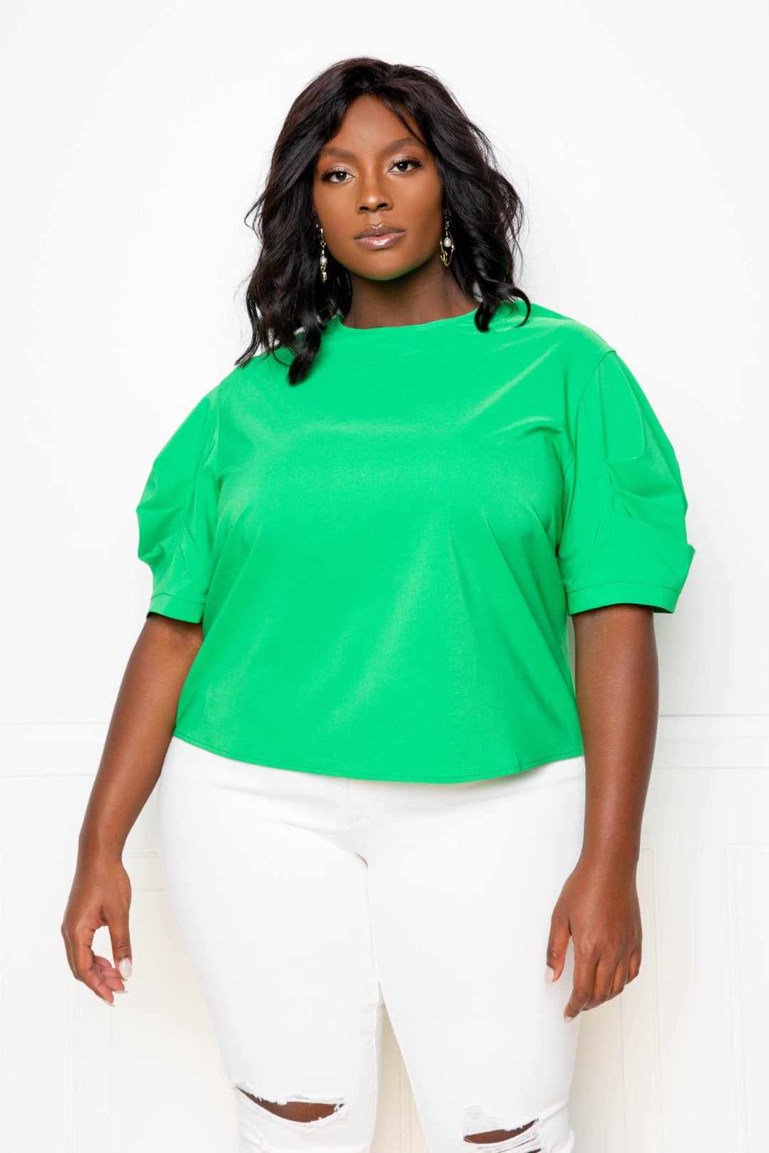 Woman wearing a green ruched puff sleeve blouse top with white jeans, plus size fashion.