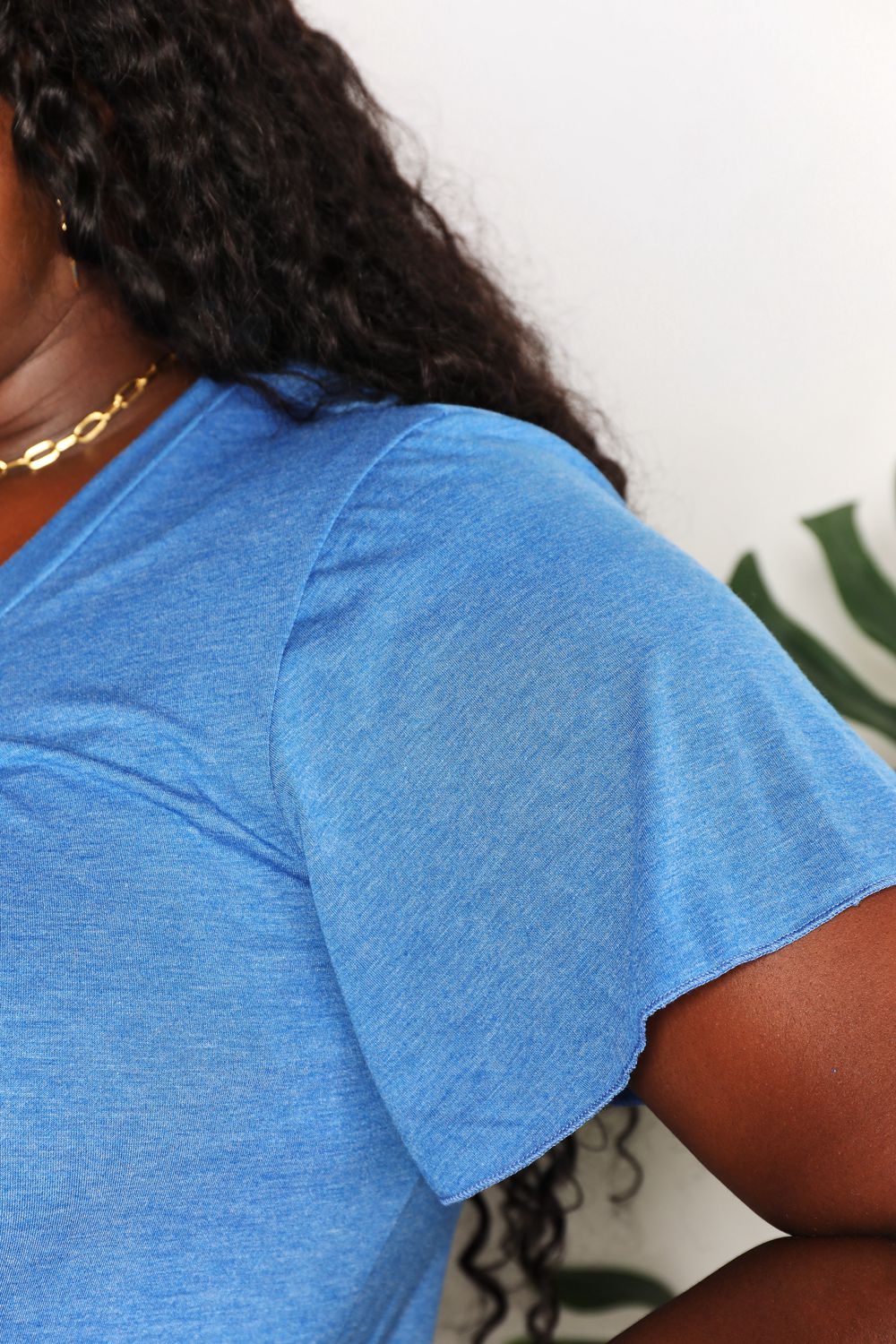 Close-up of blue Double Take Ruched V-Neck Short Sleeve T-Shirt with flutter sleeves, showcasing soft fabric and ruched design.