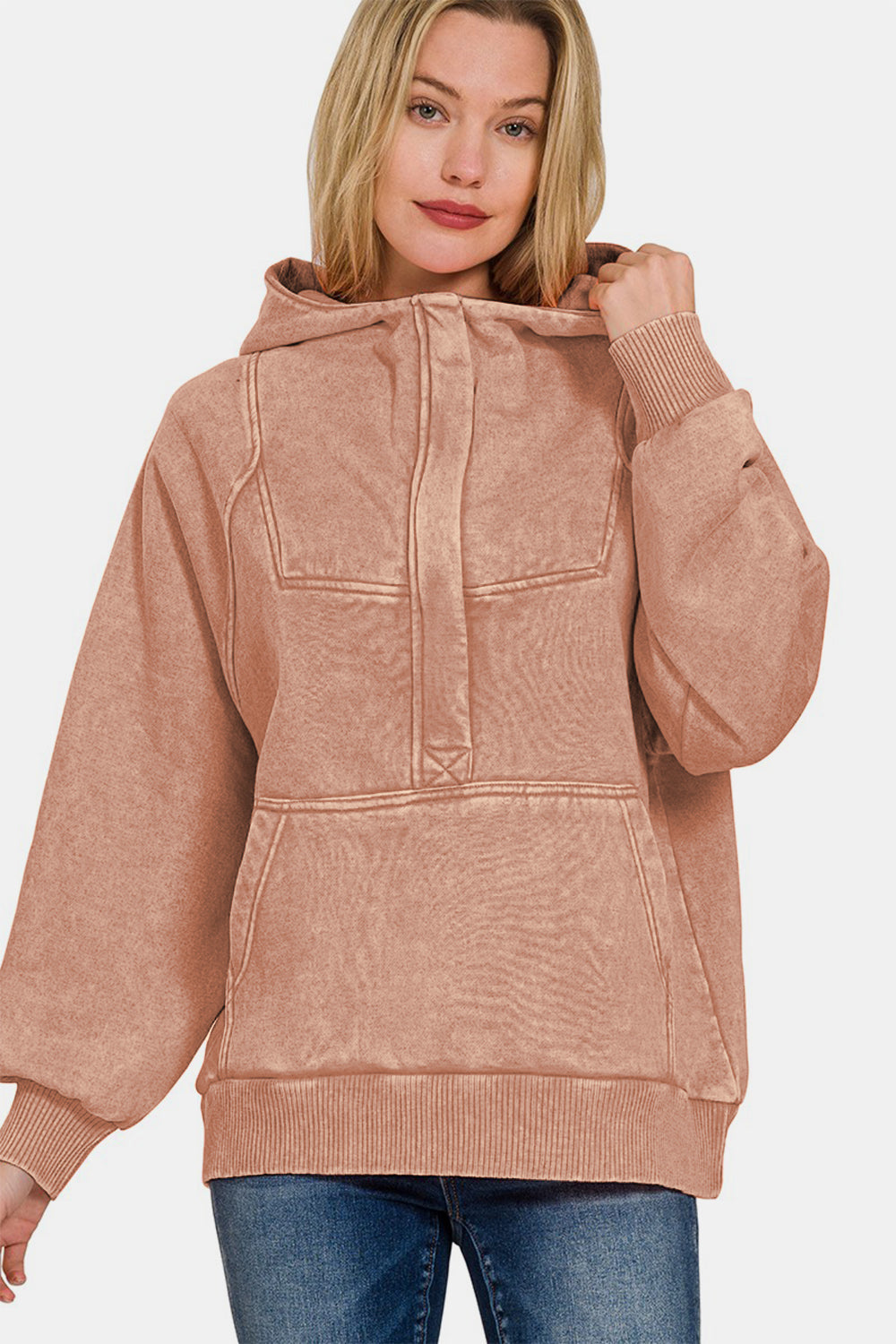 Woman wearing rust acid wash fleece kangaroo hoodie with front pocket, ribbed cuffs, and relaxed fit, made of cotton and polyester.