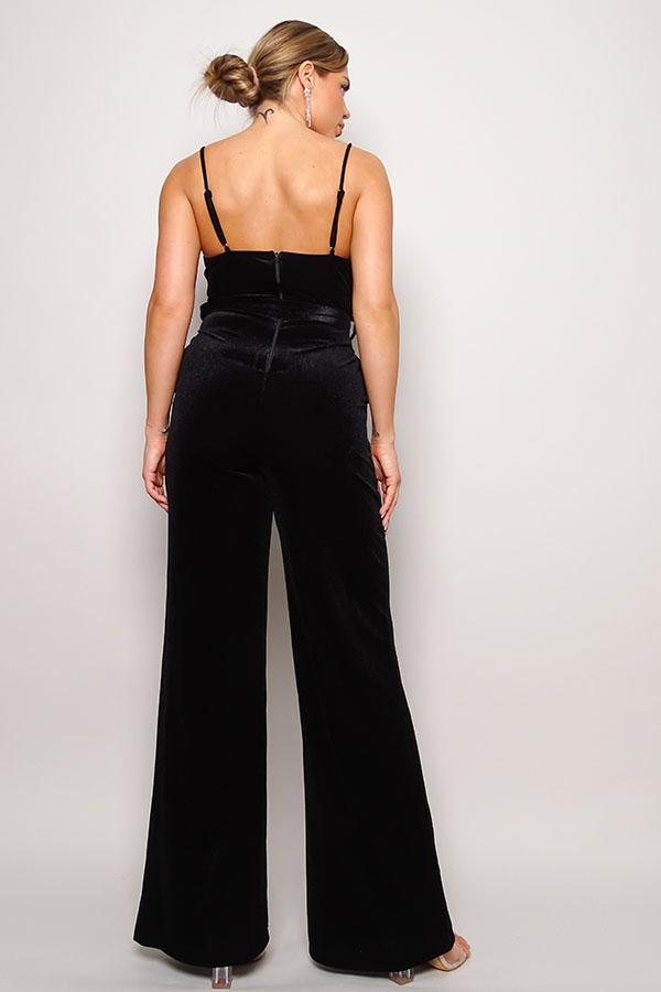 Back view of black velvet jumpsuit with rhinestone belt, featuring adjustable spaghetti straps and long pants.