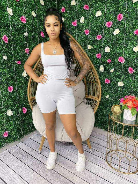 Woman wearing seamless scoop neck crop top and biker short set stands confidently in front of floral backdrop.