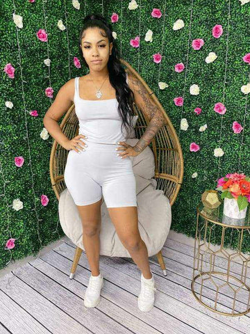 Woman wearing seamless scoop neck crop top and biker short set stands confidently in front of floral backdrop.