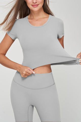 Woman wearing grey seamless short sleeve crop tee, showcasing its stretch fit and comfort.