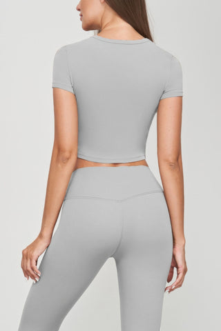 Back view of woman wearing grey seamless short sleeve crop tee and leggings, showcasing sleek, fitted silhouette. Perfect for casual wear.