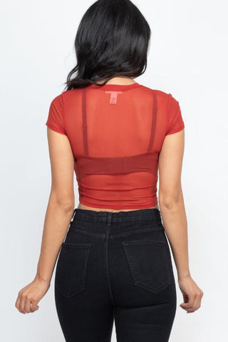 Back view of red mesh sheer short sleeve crop top, worn with black jeans.