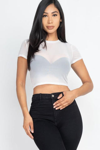 Woman wearing sexy mesh sheer short sleeve crop top in white, paired with black jeans.