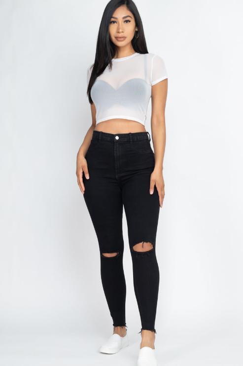 Woman wearing a sexy mesh sheer short sleeve crop top with black jeans, showcasing the trendy style and comfortable fit.