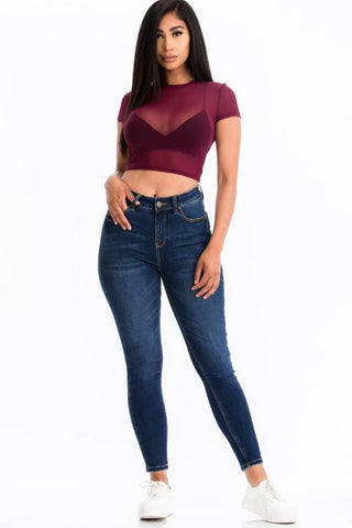 Model wearing sexy mesh sheer short sleeve crop top in burgundy, paired with blue jeans and white sneakers.