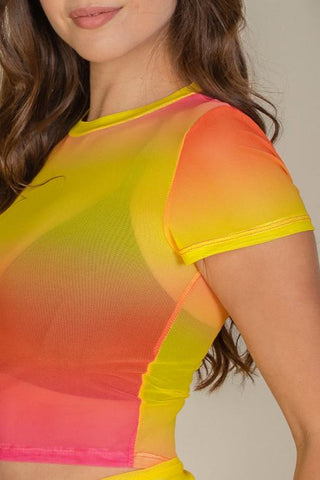 Woman wearing colorful mesh sheer short sleeve crop top, featuring vibrant orange, yellow, and pink hues.