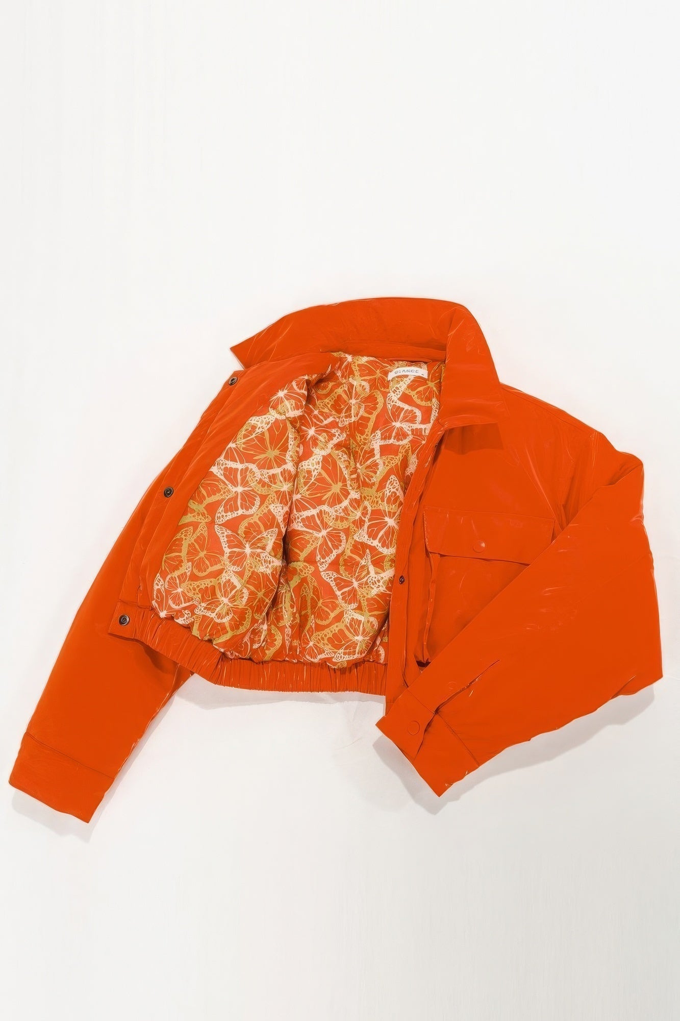 Orange puffer bomber jacket with patterned lining, featuring snap button closure and relaxed fit.