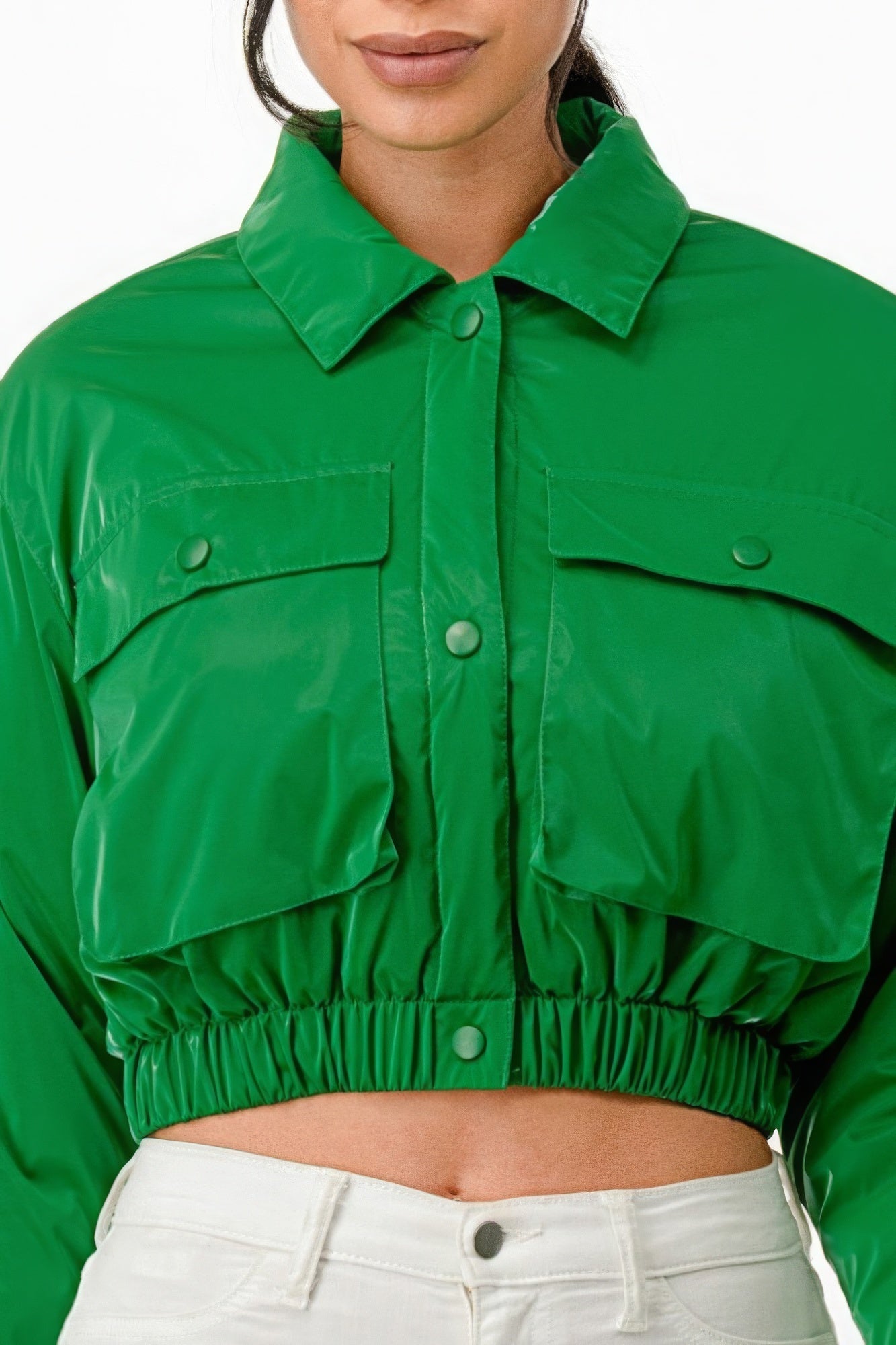 Green shiny cropped bomber jacket with snap buttons and two front pockets, worn by a model.