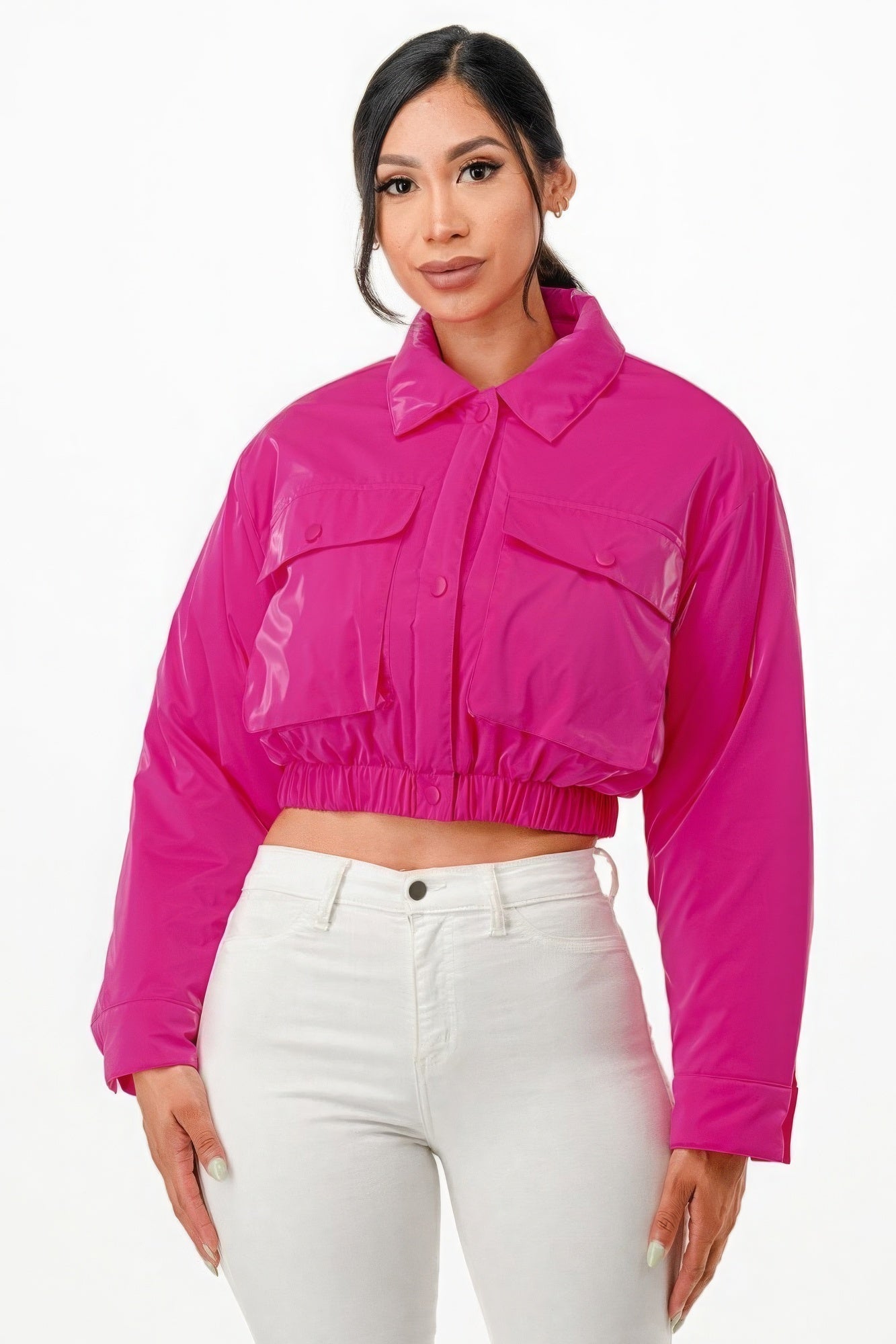 Woman wearing pink shiny cropped puffer bomber jacket with snap button closure and two front pockets.