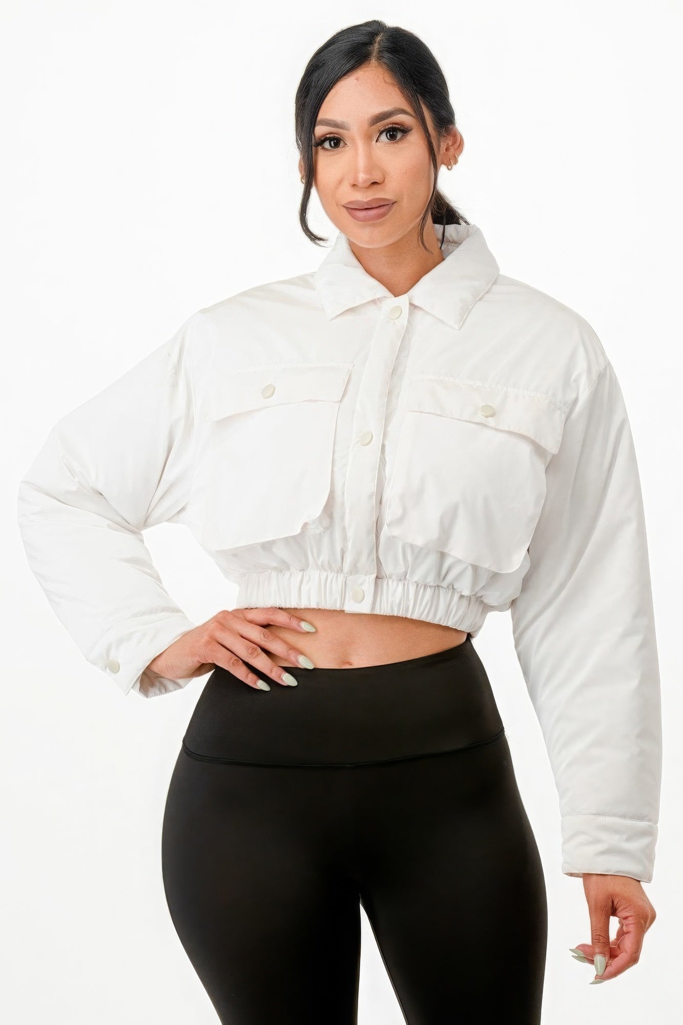 Woman wearing cropped white puffer bomber jacket with two front pockets and snap button closure.