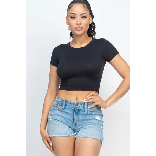 Woman wearing a black short sleeve roundneck crop top paired with denim shorts, showcasing casual summer fashion style.
