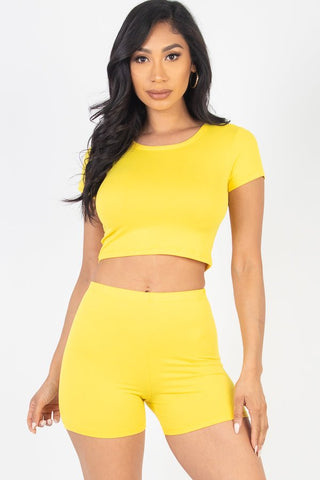 Model wearing a yellow short sleeve crop top and shorts set, made from soft, high-stretch jersey fabric, 92% polyester, 8% spandex.