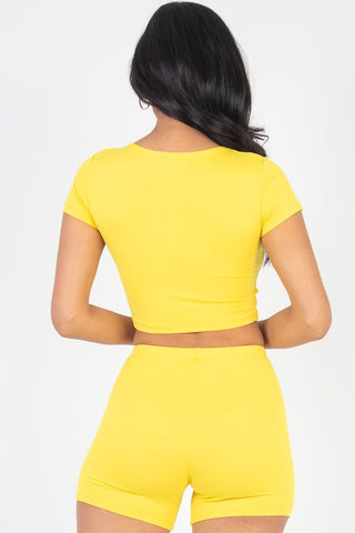 Woman wearing a vibrant yellow short sleeve crop top and shorts set, showcasing soft, lightweight high stretch jersey fabric.