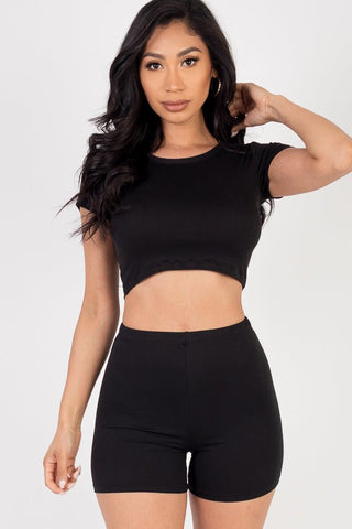 Woman wearing a black short sleeve crop top and shorts set made from soft, stretchy jersey featuring 92% polyester and 8% spandex.