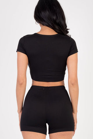 Back view of model wearing a black short sleeve crop top and shorts set, made from soft, high stretch jersey fabric.