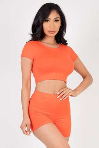 Model wearing orange short sleeve crop top and shorts set, made of soft, lightweight jersey fabric, showcasing a casual fashion look.