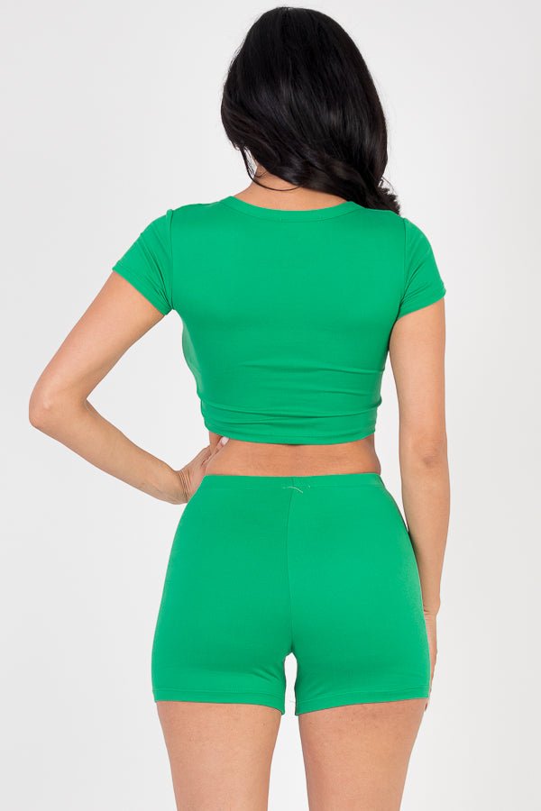 Woman wearing a green short sleeve crop top and shorts set, showcasing high stretch jersey fabric, rear view, fashion clothing