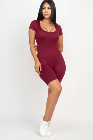 Model wearing a burgundy short sleeve scoop neck bodycon romper, showcasing its tight fit and stretchy fabric, paired with white sneakers.