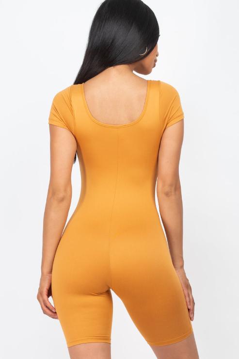 Rear view of model wearing a short sleeve scoop neck bodycon romper in mustard, showcasing a tight fit and stretchy material.