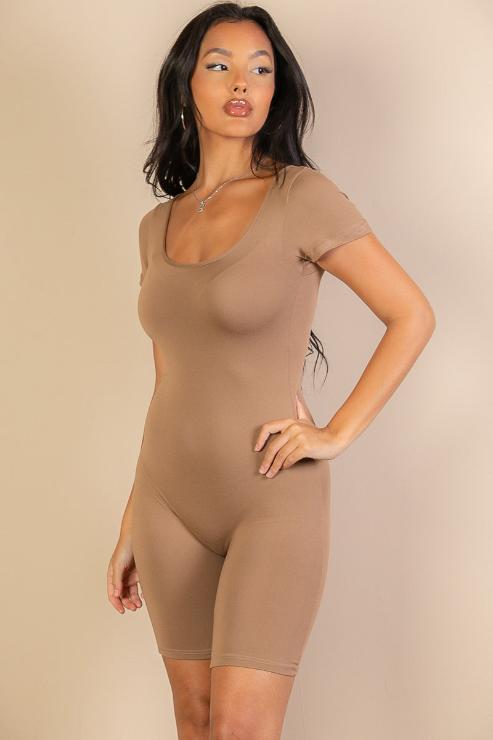Woman wearing a short sleeve scoop neck bodycon romper in beige. Lightweight, stretchy fabric with a comfortable fit. Model height: 5'8", size Small.