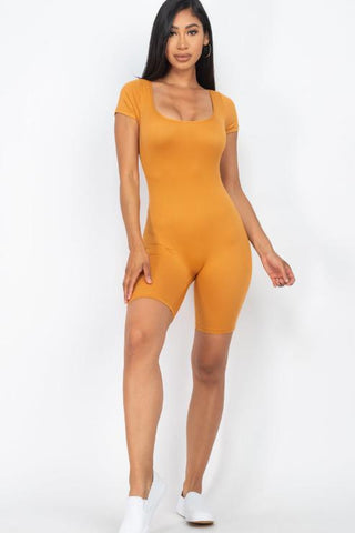 Woman wearing orange short sleeve scoop neck bodycon romper, showing front view with a snug fit. Model is 5'8" and wearing size Small.
