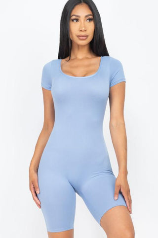 Model wearing a light blue short sleeve scoop neck bodycon romper made of stretchy polyester and spandex.