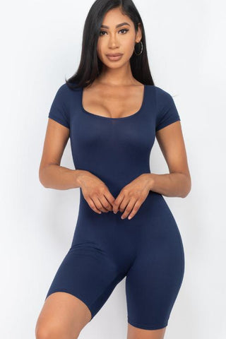 Woman wearing a navy short sleeve scoop neck bodycon romper, showcasing stretchy and comfortable fit.