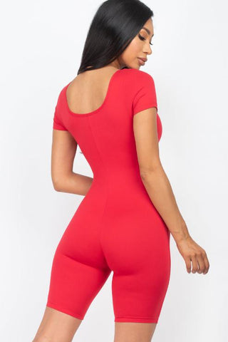 Woman wearing a red short sleeve scoop neck bodycon romper, showcasing a sleek back view. Perfect fit and stretchy fabric for comfort.