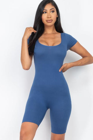 Woman wearing a blue short sleeve scoop neck bodycon romper, showing a snug fit. Made from 92% polyester and 8% spandex. Length: 31".