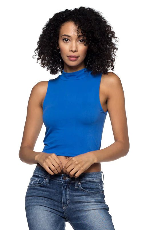 Woman wearing a sleeveless mock neck crop top in blue, paired with jeans, highlighting fitted design and stretch knit fabric.