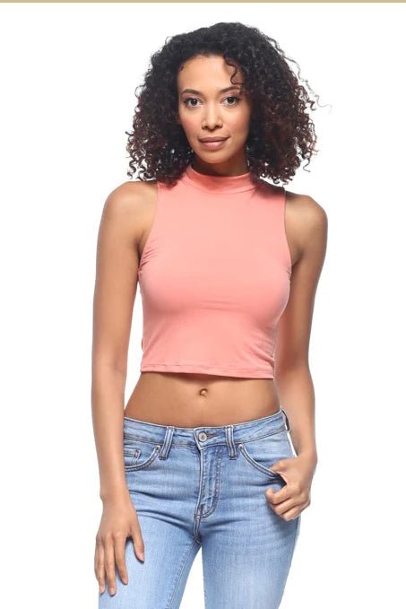 Woman wearing sleeveless mock neck crop top in peach, skinny jeans, showcasing stretch knit fabric and fitted design.
