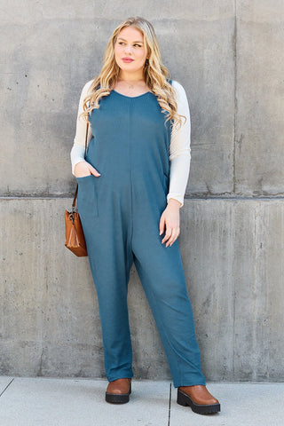 Woman wearing sleeveless straight jumpsuit with pockets, opaque fabric, polyester and spandex blend, stylish casual outfit.