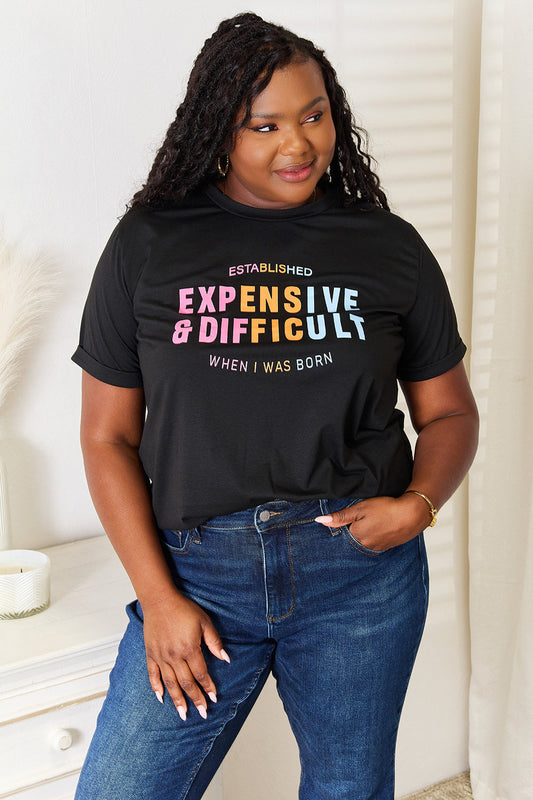 Woman wearing a black slogan graphic cuffed sleeve T-shirt with colorful text, paired with blue jeans in a casual setting.