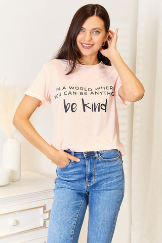 Woman wearing slogan graphic cuffed T-shirt with "Be Kind" message, showcasing casual style and comfortable fit.
